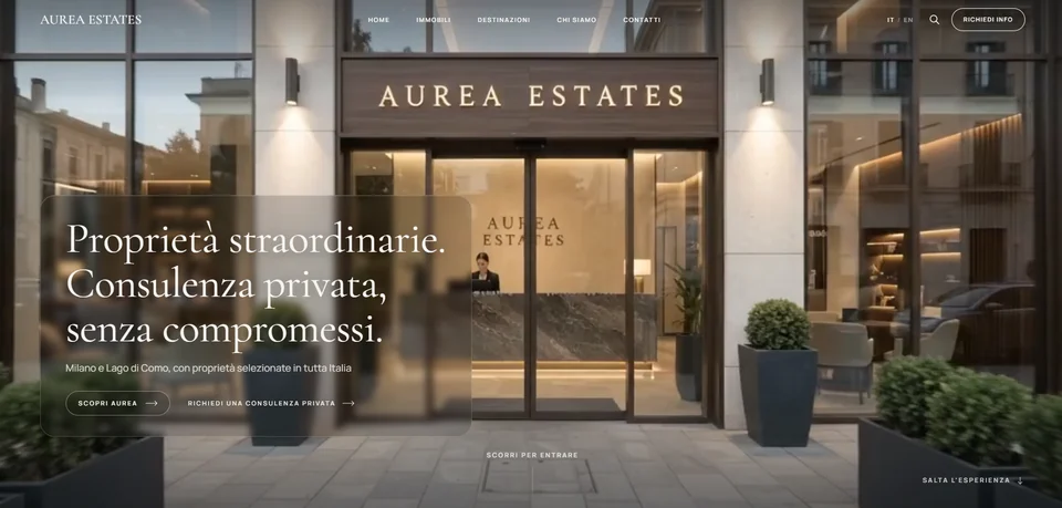 Home page del sito concept Aurea Estates: la facciata vetrata della sede con l'insegna illuminata, il titolo serif "Proprietà straordinarie. Consulenza privata, senza compromessi." in un pannello traslucido a sinistra e l'invito a scorrere per entrare.