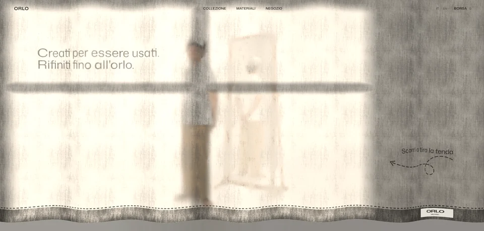 Home page del sito concept Orlo: una tenda di lino chiaro copre tutta la pagina, dietro si intravede una figura sfocata accanto a uno specchio, il titolo "Creati per essere usati. Rifiniti fino all'orlo." a sinistra e, a destra, l'invito scritto a mano a scorrere o tirare la tenda.
